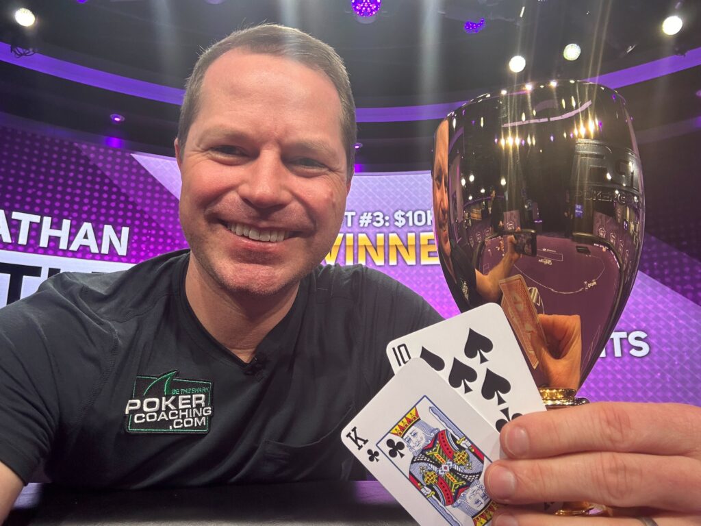 A triumphant Jonathan celebrating his first PokerGO Cup victory, holding the trophy and surrounded by poker paraphernalia.